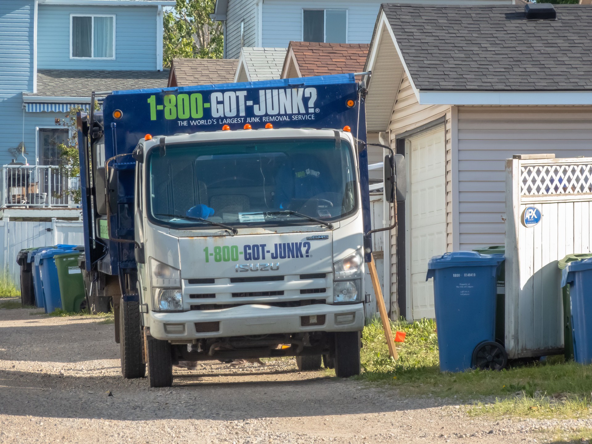 A white GOT JUNK truck parked on a residential street, ready to collect junk. The truck has the company logo and phone number on its side.