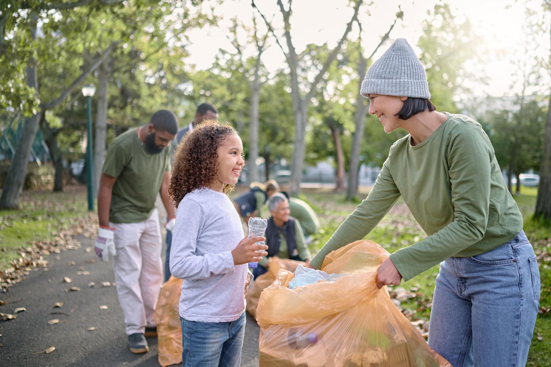 Trash volunteer, happy woman and child cleaning garbage, pollution or waste product for community environment support. Plastic bag container, NGO charity and nature park clean up by eco friendly kid